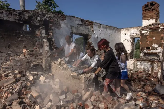 Young volunteers from the “Repair Together” initiative together with the local residents clean rubble from a house that was destroyed during the Russian invasion, at Ivanivka village, Chernihiv region, Ukraine, 30 July 2022 (issued 04 August 2022). Ivanivka village was under Russian occupation months ago and suffered heavy damage. The volunteer initiative “Repair Together” is made up mostly of young Ukrainians living in Kyiv and other parts of the country and some foreigners. The group of young people, most of whom before the Russian invasion were into Ukraine's nightlife party culture, in the past months has been cleaning and repairing war-damaged buildings in the Chernihiv region, helping to restore Ukrainian communities which were under Russian occupation. Calling their gatherings 'Toloka' and relying on people's donations and their own funds, the initiative that once started as a small group now gathers around 200 people on weekends. Chernihiv region was one of the most affected regions in Ukraine, becoming a battlefield with many people killed and buildings destroyed, and was partly under the Russian occupation from the beginning of the Russian invasion until early April. Russian troops on 24 February 2022 entered Ukrainian territory, starting a conflict that provoked destruction and a humanitarian crisis. (Photo by Roman Pilipey/EPA/EFE)