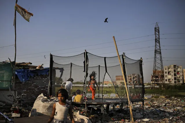 In this Tuesday, March 17, 2020 photo, children play next to a drain filled with plastic and other filth at a slum in New Delhi, India. (Photo by Altaf Qadri/AP Photo)