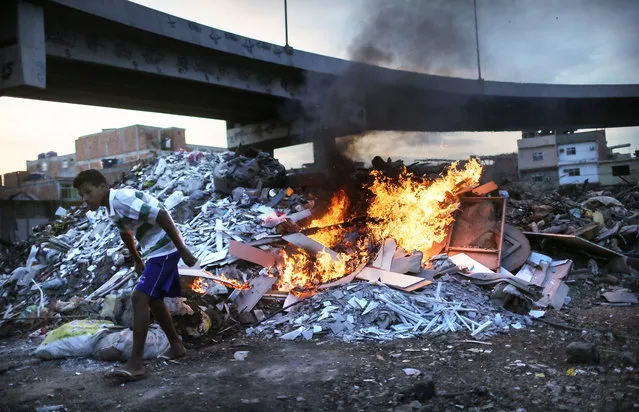 Trash is burned in an area where garbage is dumped near the main highway linking Rio's international airport to the city in the Mare favela community complex on July 18, 2016 in Rio de Janeiro, Brazil. The Mare complex is one of the largest favela complexes in Rio and is challenged by violence, pollution and poverty. The Rio 2016 Olympic Games begin August 5. (Photo by Mario Tama/Getty Images)