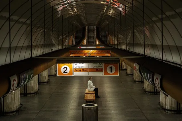 A woman wearing a face mask sits on a bench at an empty metro station on April 15, 2020 in Prague amid restrictions due to the new coronavirus pandemic. (Photo by Michal Cizek/AFP Photo)