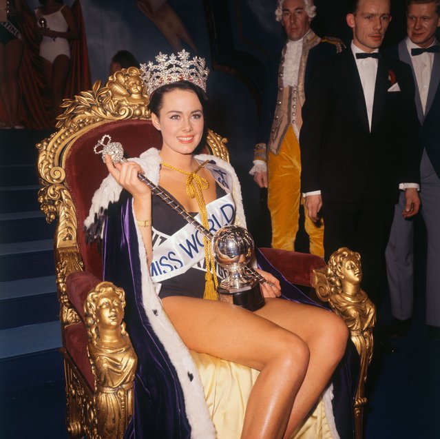 Ann Sidney, seated on throne wearing robes and crown, holds scepter and trophy after being selected Miss World in the ballroom of the Lyceum Theater on November 12, 1964 in London, England. Ann entered the contest as Miss United Kingdom. (Photo by Bettmann/Getty Images)