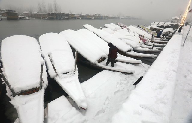 A man arrives to clear snow from his boat at Dal Lake in Srinagar , the summer capital of Indian Kashmir, 28 December 2024. The plains in Kashmir received snowfall on the second consecutive day, bringing to an end a much-extended dry spell. (Photo by Farooq Khan/EPA)