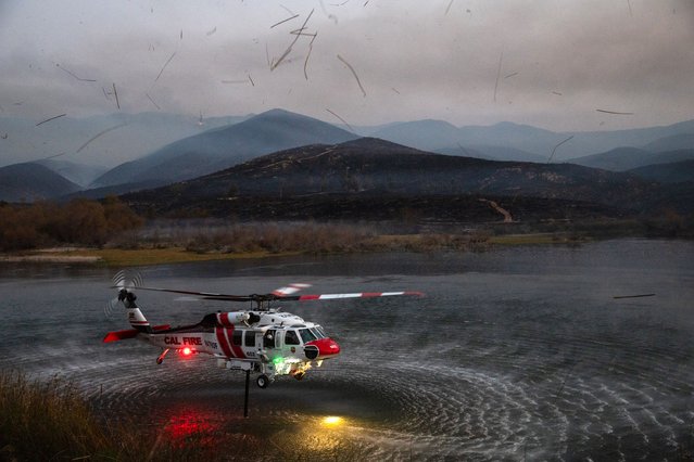 A Cal Fire helicopter picks up water from Lower Otay Lake to fight the Border Fire in San Diego, California, on January 24, 2025. (Photo by Zoe Meyers/AFP Photo)