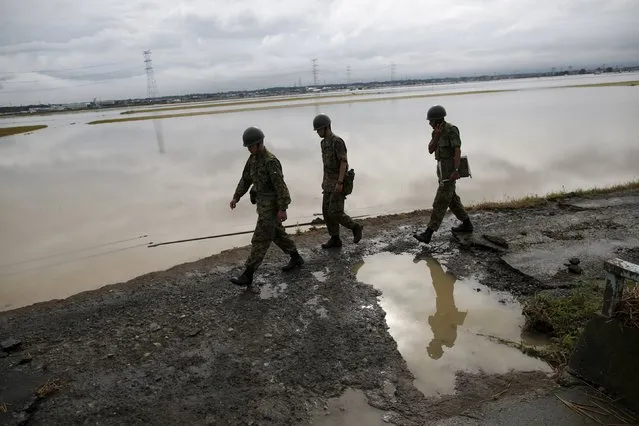 Japanese Self-Defence Force soldiers walk at an area flooded by the Kinugawa river, caused by typhoon Etau in Joso, Ibaraki prefecture, Japan, September 11, 2015. (Photo by Issei Kato/Reuters)