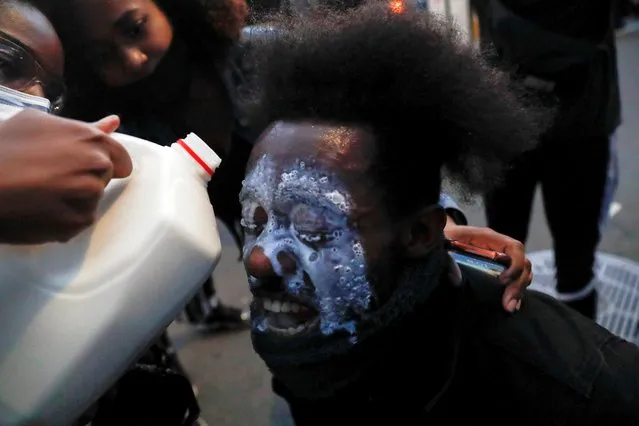 Protesters help a man whose eyes are affected by tear gas during an “I can't breathe” vigil and rally in the Brooklyn borough of New York, NY, U.S., following the death of African-American George Floyd who was seen in graphic video footage gasping for breath as a white officer knelt on his neck in Minneapolis, Minnesota, May 29, 2020. (Photo by Shannon Stapleton/Reuters)