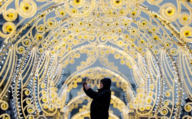 A man takes photos via his smartphone while standing next to street decorations in Moscow, Russia, on February 13, 2025. (Photo by Maxim Shemetov/Reuters)