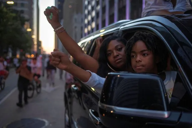 Brooklyn Prince, 8, sits in the lap of Ashley Prince as they hold out their hands in solidarity with other protesters during a spontaneous caravan rally of vehicles against the death in Minneapolis police custody of George Floyd, through downtown Houston, Texas, U.S., June 2, 2020. (Photo by Adrees Latif/Reuters)