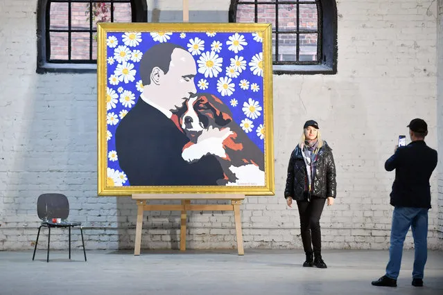 A woman poses in front of Russian artist Alexey Sergienko's painting “Putin with a puppy”, dedicated to President Vladimir Putin's upcoming 70th birthday, in Saint Petersburg on October 6, 2022. Vladimir Putin will turn 70 on October 7. (Photo by Olga Maltseva/AFP Photo)