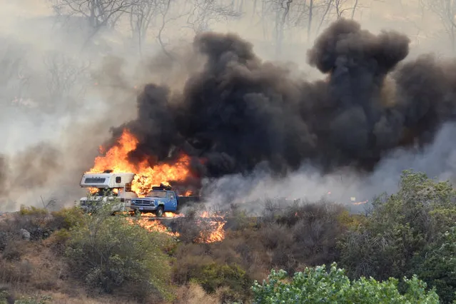 An RV and a truck are engulfed in flames from a wildfire in Devore, Calif., on Wednesday, August 17, 2016. A wildfire with a ferocity never seen before by veteran California firefighters raced up and down canyons, instantly engulfing homes and forcing thousands of people to flee, some running for their lives just ahead of the flames. Five years of drought have turned the state's wildlands into a tinder box, with eight fires currently burning from Shasta County in the far north to Camp Pendleton just north of San Diego. (Photo by David Pardo/The Daily Press via AP Photo)