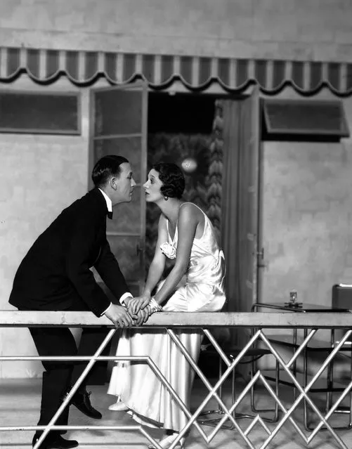 Noel Coward (1899–1973) and Gertrude Lawrence sit on a balcony staring into each other's eyes, in a scene from the play “Private Lives”, at the Phoenix Theatre, London, 1930. Costumes by Molyneux. (Photo by Sasha)