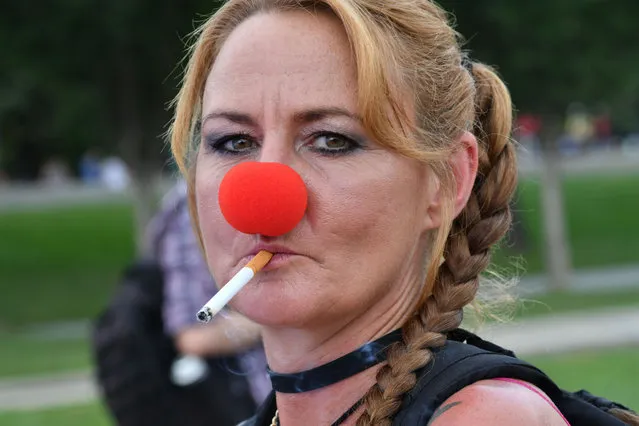 A woman wearing a clown's nose smokes a cigarette as several thousand fans of the US rap group Insane Clown Posse, known as Juggalos, prepare to assemble on September 16, 2017 near the Lincoln Memorial in Washington, D.C. to protest at a 2011 FBI decision to classify their movement as a gang. (Photo by Paul J. Richards/AFP Photo)