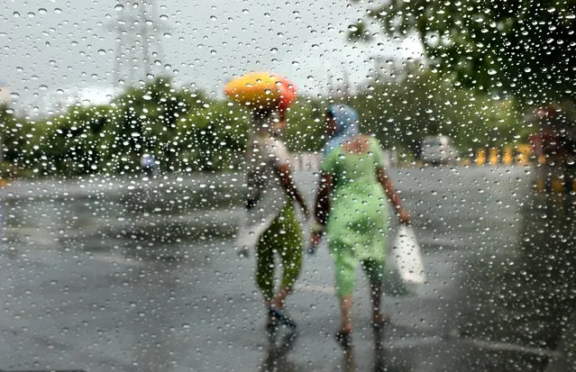Indian women are seen through a glass with rain drops after a sudden rainfall on outskirts of New Delhi, India, 25 June 2020. According to India Meteorological Department (IMD), monsoon rain will hit Delhi and to give the respite soon from the summer heat. (Photo by Harish Tyagi/EPA/EFE)