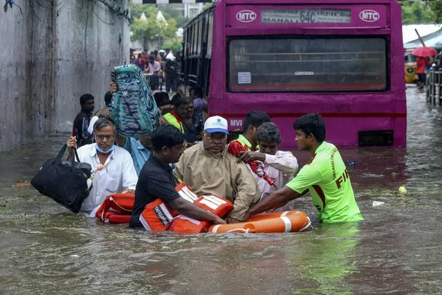 A passenger, wearing cap, of a bus that got stuck in an underpass that was flooded due to heavy rains is rescued by members of the Fire and Rescue department in Chennai, India, Tuesday, November 1, 2022. (Photo by R. Parthibhan/AP Photo)