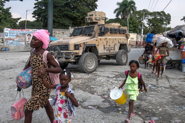 People walk on a street with their belongings as they abandon their homes due to the war between armed gangs in the Pernier area, in the commune of Petionville, today in Port-au-Prince, Haiti, on 31 January 2023. Since 2018, there has been a significant deterioration in the security situation in Haiti due to war between armed gangs with cases of kidnapping, massacre, armed attacks, robberies, and rapes of citizens increasing substantially. (Photo byJohnson Sabin /EPA/EFE)