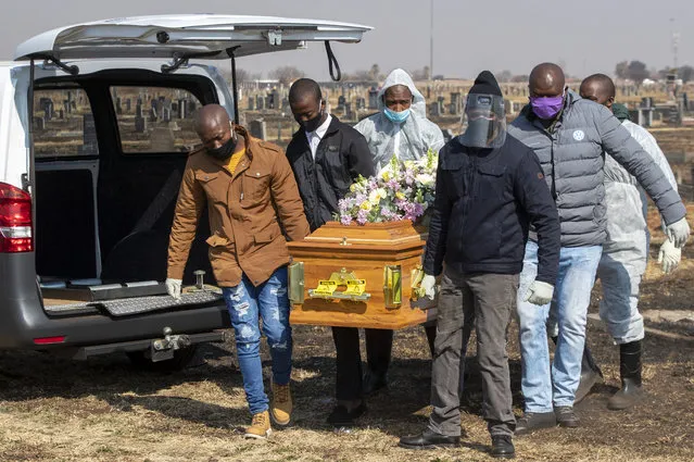 Family members and funeral workers in a protective gear, carry the coffin of nurse Duduzile Margaret Mbonane who died from COVID-19, during her funeral,  in Thokoza east of Johannesburg, South Africa, Thursday, July 23, 2020. One of the country's nurses was buried Thursday, the latest of more than 5,000 infected health workers across South Africa. Mbonane died just a month before her retirement, her husband said. (Photo by Themba Hadebe/AP Photo)