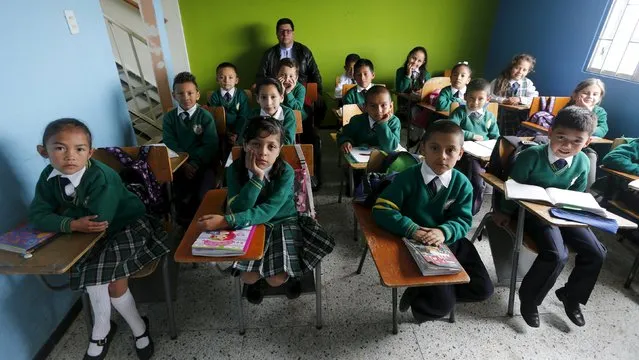 Teacher Father Juan Humberto Cruz poses for pictures with 4th grade students at Semillas de Esperanza (Seeds of Hope) school in Soacha, near Bogota, Colombia, June 11, 2015. (Photo by John Vizcaino/Reuters)