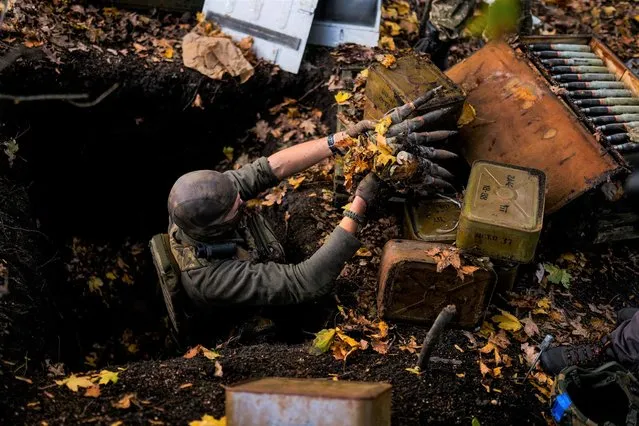 A Ukrainian territorial defence deminer takes Russian ammunition left behind as his team clears mines near Grakove village, Ukraine, Thursday, October 13, 2022. (Photo by Francisco Seco/AP Photo)
