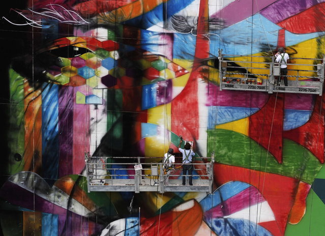 Brazilian graffiti artist Eduardo Kobra (C) puts the final touches to his piece of art in tribute to Brazilian architect Oscar Niemeyer, next to his assistants, at the financial center on Sao Paulo's Avenida Paulista January 22, 2013. Kobra created the 56-metre (61-yard) tall graffiti artwork as a tribute to Niemeyer, one of the 20th century's most influential modernist architects. Niemeyer died in December 2012, aged 104. REUTERS/Nacho Doce (BRAZIL - Tags: SOCIETY TPX IMAGES OF THE DAY)
