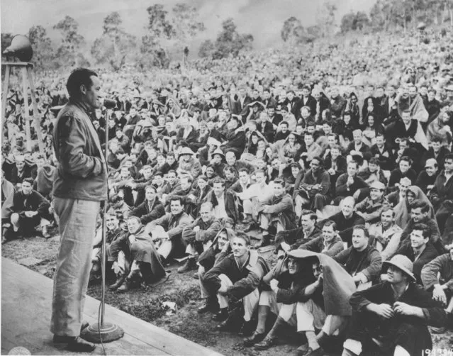 Comedian Bob Hope entertains a large crowd of G.I.s, mostly patients who are wrapped in blankets, at a hospital in New Caledonia in the Pacific during World War II on October 18, 1944.  Hope is on his United Service Organizations (USO) tour to entertain troops serving overseas. (Photo by AP Photo/ACME)
