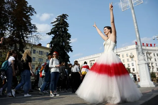 An opposition supporter in the colours of the old Belarus flag, gestures a V-sign during a rally to protest against the presidential election results in Minsk on September 12, 2020. Belarus strongman Alexander Lukashenko, 66, who has been in power for 26 years, has vowed that he will not give up power to the opposition, which claims its candidate Svetlana Tikhanovskaya was the rightful winner of the August 9 polls. (Photo by TUT.BY/AFP Photo)