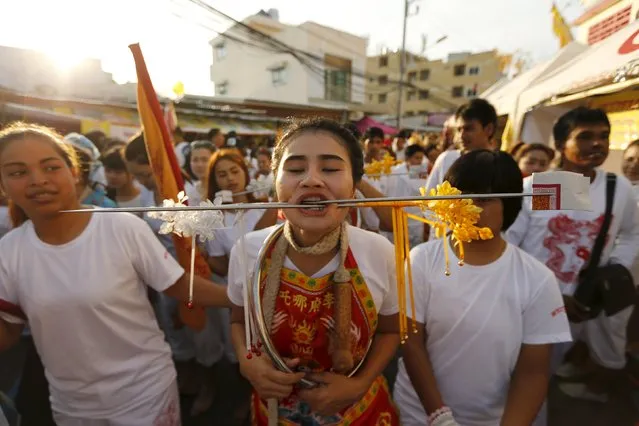 A devotee of the Chinese Jui Tui shrine walks with spikes pierced through her cheeks during a procession celebrating the annual vegetarian festival in Phuket, Thailand October 19, 2015. (Photo by Jorge Silva/Reuters)