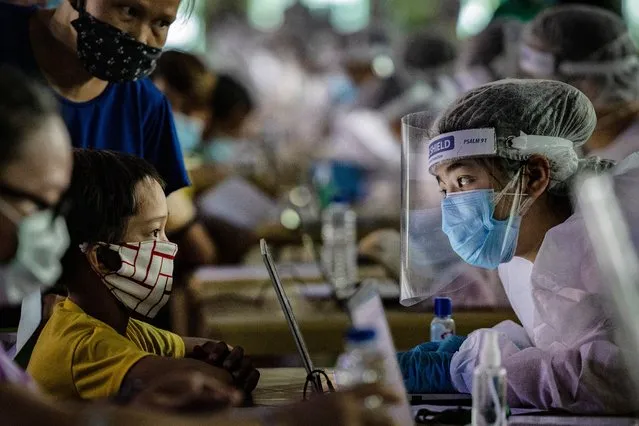 A medical worker wearing personal protective equipment interviews a child queueing for free COVID-19 swab testing at a basketball court on August 6, 2020 in Navotas city, Metro Manila, Philippines. President Rodrigo Duterte has reimposed a strict lockdown in capital Manila and surrounding provinces as the country continues to struggle with rising coronavirus infections which has breached 100,000 cases. Duterte's move came after nearly 100 medical organizations representing 80,000 doctors and a million nurses called for tighter controls and warned that the country's health systems has been overwhelmed by the surge of cases and are close to collapsing as health workers fall ill or resign out of fear and exhaustion. (Photo by Ezra Acayan/Getty Images)