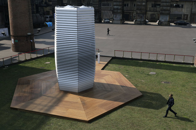 Dutch artist Daan Roosegaarde, right, walks by his Smog Free Tower on display at D-751art district in Beijing, Thursday, September 29, 2016. In a city where smog routinely blankets the streets and chokes off clean air, Roosegaarde has offered an eccentric solution: a 20-foot metal tower that takes in smog and purifies it like a giant outdoor vacuum cleaner. (Photo by Andy Wong/AP Photo)