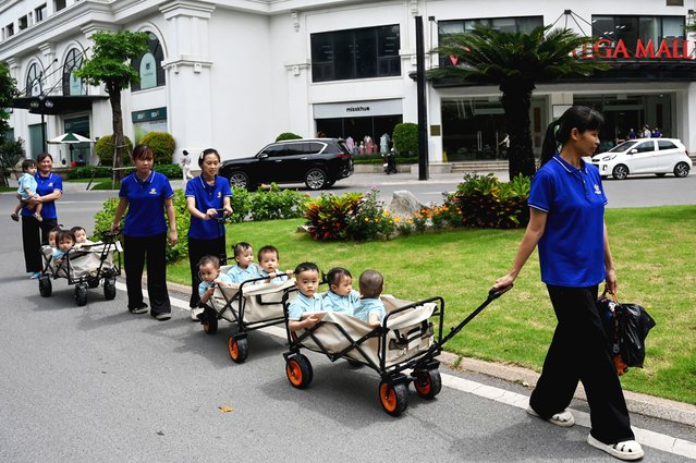 Childcare teachers take children for a ride in small carts in a residential area in Hanoi on July 10, 2025. (Photo by Nhac Nguyen/AFP Photo)