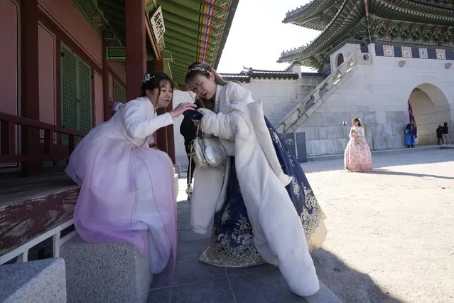 Hong Kong travelers wearing South Korean traditional “Hanbok” costume watch a smartphone at the Gyeongbok Palace, the main royal palace during the Joseon Dynasty, and one of South Korea's well known landmarks in Seoul, South Korea, on January 18, 2023. The expected resumption of group tours from China is likely to bring far more visitors. (Photo by Ahn Young-joon/AP Photo)