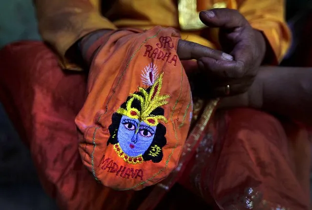 A priest prays holding a bag with an image of the Hindu God Krishna at the Ladali  in Barsana. (Photo by Manish Swarup/Associated Press)