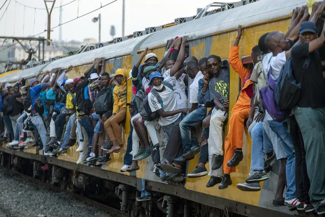 In this Monday, March 16, 2020 file photo, train commuters hold on to the side of an overcrowded passenger train in Soweto, South Africa. Up to 150 million people could slip into extreme poverty, living on less than $1.90 a day, by late next year depending on how badly economies shrink during the COVID-19 pandemic, the World Bank said Wednesday, Oct. 7, 2020 in an outlook grimmer than before. (Photo by Themba Hadebe/AP Photo/File)