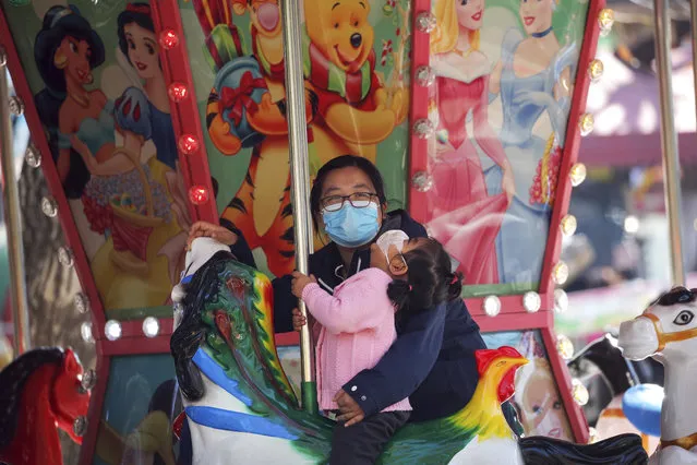 A woman and a child, both wearing face masks to help curb the spread of the coronavirus, ride on a carousel horse at a park in Beijing, Tuesday, November 10, 2020. Authorities in China's financial hub of Shanghai have quarantined 186 people and conducted coronavirus tests on more than 8,000 after a freight handler at the city's main international airport tested positive for the virus. (Photo by Andy Wong/AP Photo)