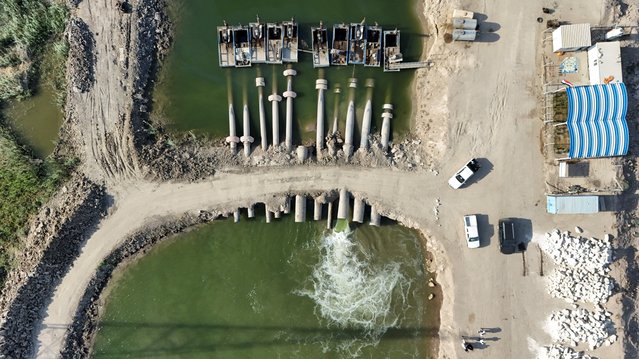 A drone view shows a water pumping system operating on the banks of the Euphrates River to irrigate marsh areas affected by drought in Basra, Iraq, on August 20, 2025. Iraq, one of the countries most affected by climate change, faces severe drought, prompting farmers to adopt hydroponic barley grown in climate-controlled units. (Photo by Mohammed Aty/Reuters)