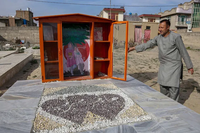 A man opens the door of a library on the grave of Marzia, 18, and Hajar, 19, in Kabul, Afghanistan, 22 March 2023 (issued 24 March 2023). The two cousins were killed among tens of other students, mostly female, who had gathered for a practice university entrance exam at an institute of Kabul in September 2022, following a suicide bomb attack. In tribute to the girls, their families placed a library with their favorite books on their grave at a graveyard in Dasht-e-barchi area. (Photo by Samiullah Popal/EPA/EFE)