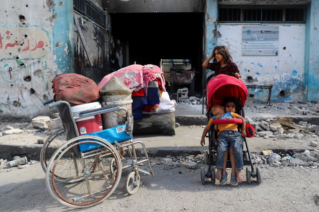A girl stands next to a stroller, as two children sit in it, while displaced Palestinians get ready to flee, amid an Israeli military operation, after Israeli forces ordered residents of Gaza City to evacuate to the south, in Gaza City, on September 19, 2025. (Photo by Ebrahim Hajjaj/Reuters)