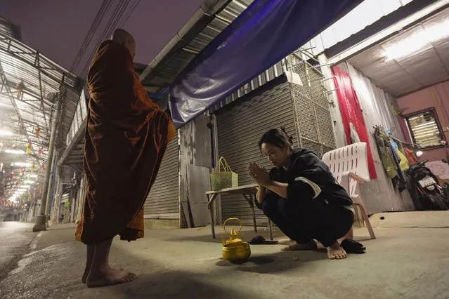 Thanaporn Phromthep, right, mother of Duangphet Phromthep, prays after offering food to a Buddhist monk in front of her house in Chiang Rai province, Thailand, Sunday, March 5, 2023. The cremated ashes of Duangphet, one of the 12 boys rescued from a flooded cave in 2018, arrived in the far northern Thai province of Chiang Rai on Saturday where final Buddhist rites for his funeral will be held over the next few days following his death in the U.K. (Photo by Sakchai Lalit/AP Photo)