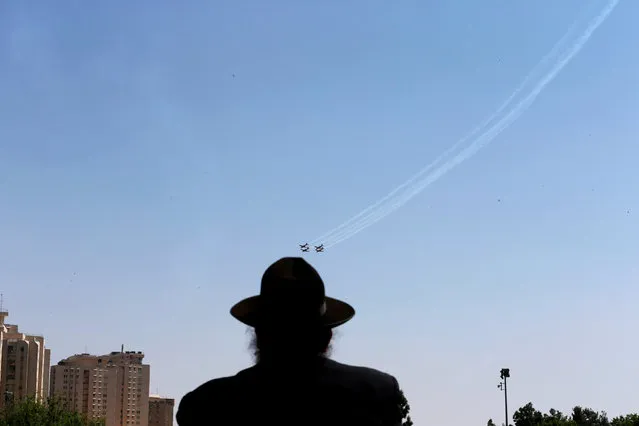 An Ultra Orthodox Jewish man looks at an Israeli Air Force aerobatic team flying in formation during a rehearsal for an aerial show for Israel's 70th Independence Day celebrations, in Jerusalem, April 16, 2018. (Photo by Ammar Awad/Reuters)
