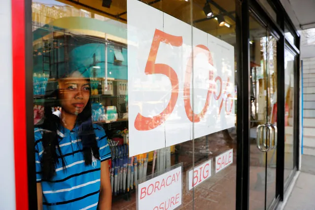 A saleswoman looks out from a glass window of a clothing store, a day before the temporary closure of the holiday island Boracay in the Philippines April 25, 2018. (Photo by Erik De Castro/Reuters)