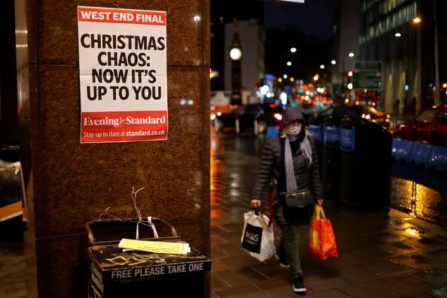A shopper wears a facemask as she walks past an Evening Standard newspaper stand at Victoria Station in central London on December 16, 2020, as new guidance on Christmas during the novel coronavirus COVID-19 pandemic was announced by the government. Prime Minister Boris Johnson resisted calls to tighten coronavirus restrictions over Christmas, as London faced stricter measures and concern mounted about case numbers. (Photo by Tolga Akmen/AFP Photo)