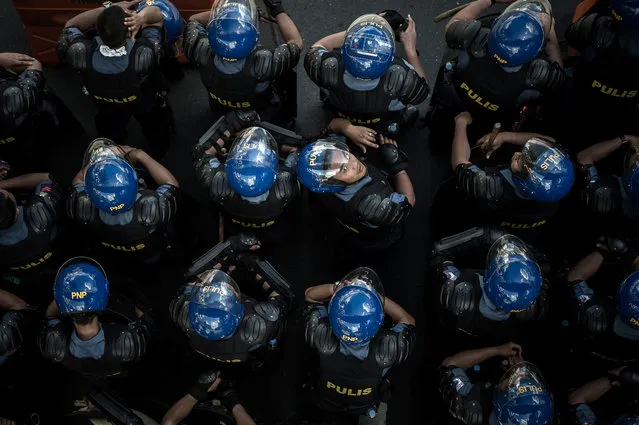 A Philippine policeman looks up as they keep vigil after protesters staged a demonstration in opposition to the Asia-Pacific Economic Cooperation (APEC) Summit currently in Manila on November 19, 2015. Police pumped out Katy Perry pop songs on loudspeakers and fired water cannons to disperse protesters at the Asia-Pacific leaders summit, with bewildered demonstrators denouncing the music tactics as "ridiculous". (Photo by Philippe Lopez/AFP Photo)