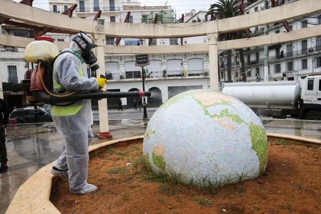 A worker wearing a protective suit disinfects a globe-shaped public garden, following the outbreak of coronavirus disease (COVID-19), in Algiers, Algeria on March 23, 2020. (Photo by Ramzi Boudina/Reuters)