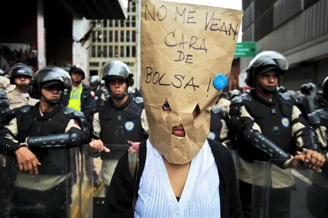 A public university teacher wears a brown bag that reads “Don't see me as a bag face”, loosely translated as “Don't take me for an idiot”, during a protest in Caracas, Venezuela, on May 22, 2013. Teachers are demanding wage increases. (Photo by Fernando Llano/Associated Press)