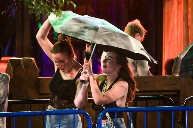 Revellers battled against 40mph winds and driving rain to get to nightclubs in Birmingham city centre on September 21, 2025. The Met Office released a yellow weather warning for strong wind and heavy rain overnight across much of England and Wales. The partygoers used their coats and umbrellas to shelter from the barmy conditions. (Photo by British News and Media/Alamy Live News)