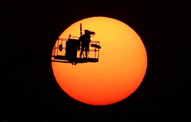 A television cameraman is silhouetted by the sun during a practice session for the Qatar Grand Prix in Lusail on November 28, 2025. (Photo by Mohammed Salem/Reuters)