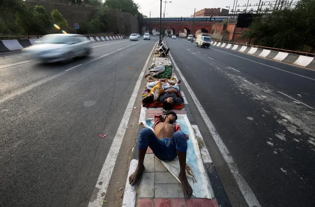 People sleep on a road divider in New Delhi, India, June 1, 2018. (Photo by Amit Dave/Reuters)