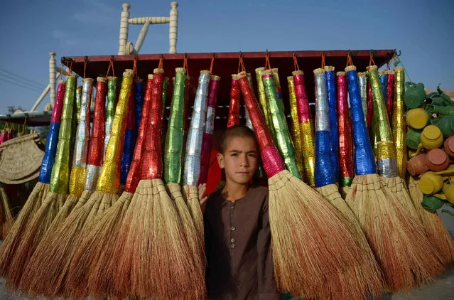 In this photograph taken on May 30, 2018, Afghan vendor Rafi, 9, poses for a photograph as he sell brooms at a roadside stall in Mazar- i-Sharif. (Photo by Farshad Usyan/AFP Photo)