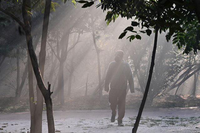 A man walks at a park amid dense smog in Lahore on December 12, 2025. (Photo by Arif Ali/AFP Photo)