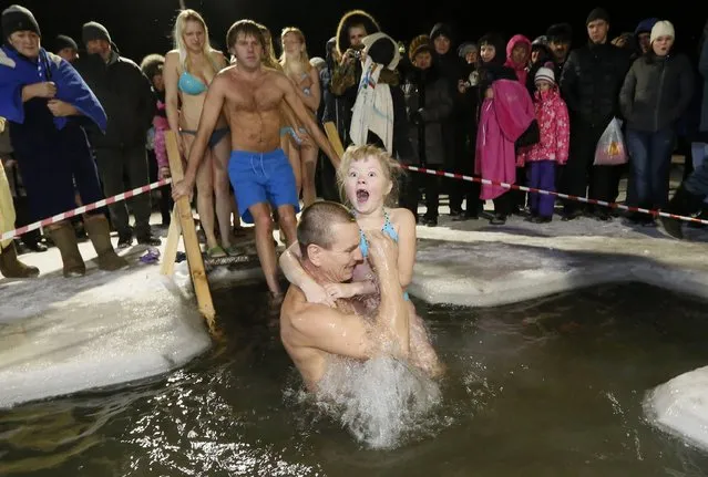 A man and his daughter immerse themselves in an ice hole in the Chulym river, with the air temperature at about minus 12 degrees Celsius (10.4 degrees Fahrenheit), during celebrations for Russian Orthodox Epiphany outside of the town of Nazarovo, Krasnoyarsk region January 19, 2015. (Photo by Ilya Naymushin/Reuters)
