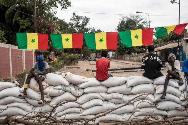 Protesters sit on top of sandbag barricades as they block the road to opposition leader Ousmane Sonko’s house in Ziguinchor, Senegal on May 22, 2023. Protesters have been blocking the roads in Ziguinchor to stop the arrest of opposition leader Ousmane Sonko ahead of his rape trail, which should start on May 24, 2023. (Photo by Muhamadou Bittaye/AFP Photo)