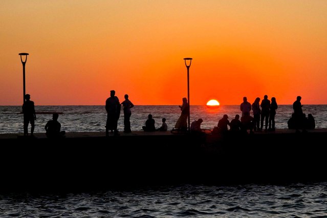 People gather along the corniche as the sun sets in the Libyan capital Tripoli on August 5, 2025. (Photo by Mahmud Turkia/AFP Photo)